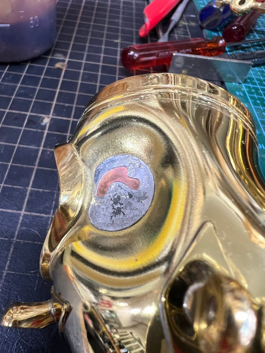 Gold saxophone body with a worn patch on the bell